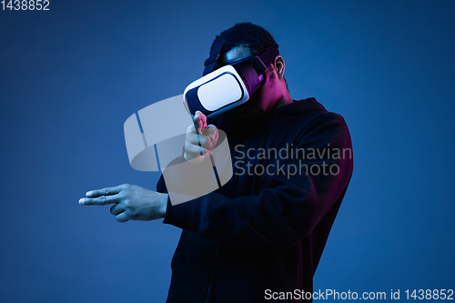 Image of Young african-american man\'s using VR-glasses in neon light