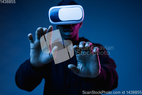 Image of Young african-american man\'s using VR-glasses in neon light