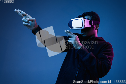 Image of Young african-american man\'s using VR-glasses in neon light