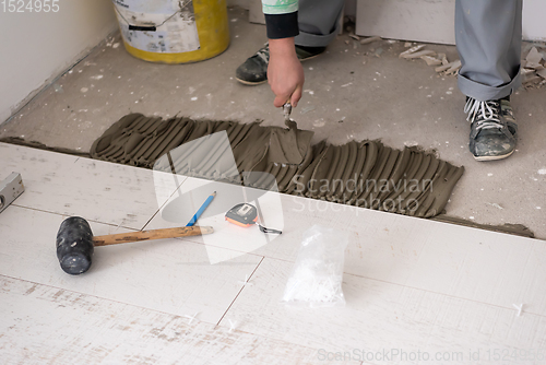 Image of worker installing the ceramic wood effect tiles on the floor