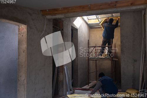 Image of roofer man installing thermal insulation layer