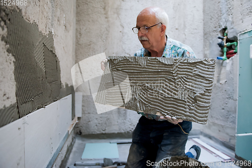 Image of worker installing big ceramic tiles