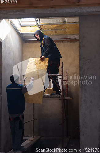 Image of roofer man installing thermal insulation layer