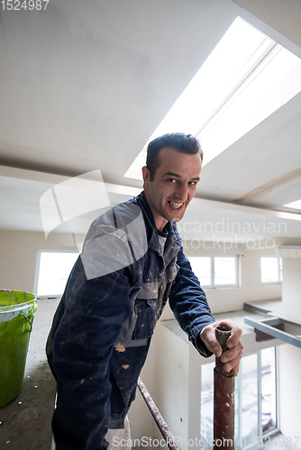 Image of construction worker plastering on gypsum ceiling