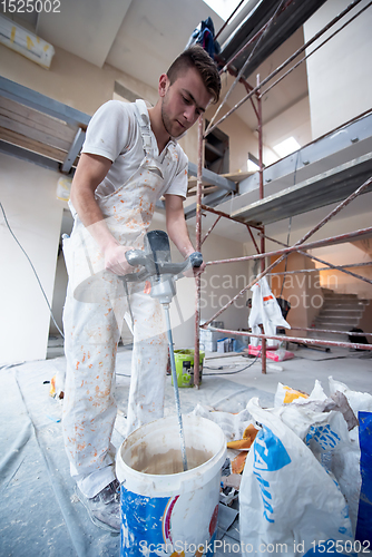 Image of construction worker mixing plaster in bucket