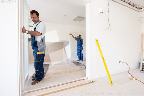 Image of carpenters installing glass door with a wooden frame