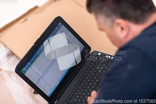 Image of man using laptop while lying on cardboard box