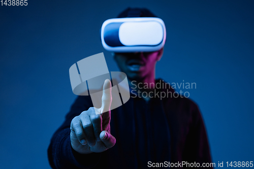 Image of Young african-american man\'s using VR-glasses in neon light
