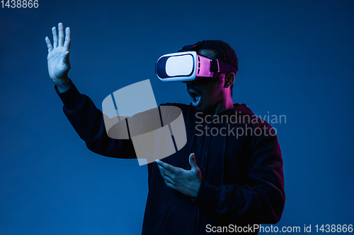 Image of Young african-american man\'s using VR-glasses in neon light