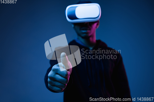 Image of Young african-american man\'s using VR-glasses in neon light