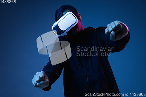 Image of Young african-american man\'s using VR-glasses in neon light