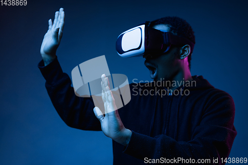 Image of Young african-american man\'s using VR-glasses in neon light