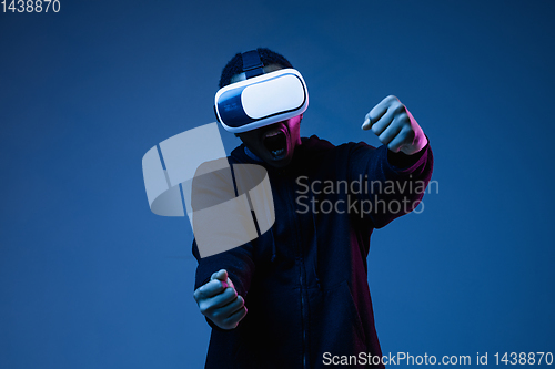 Image of Young african-american man\'s using VR-glasses in neon light