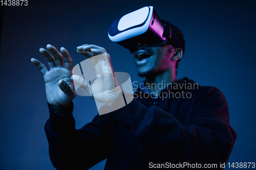 Image of Young african-american man\'s using VR-glasses in neon light