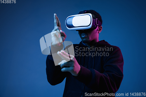 Image of Young african-american man\'s using VR-glasses in neon light