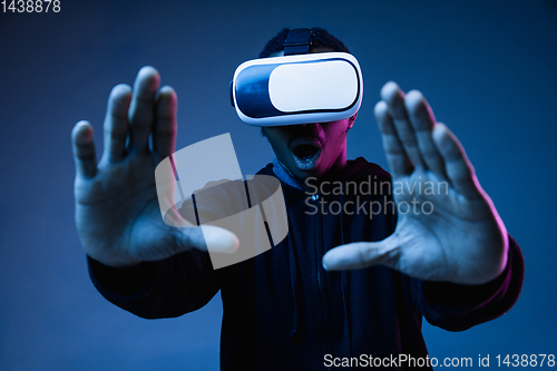 Image of Young african-american man\'s using VR-glasses in neon light