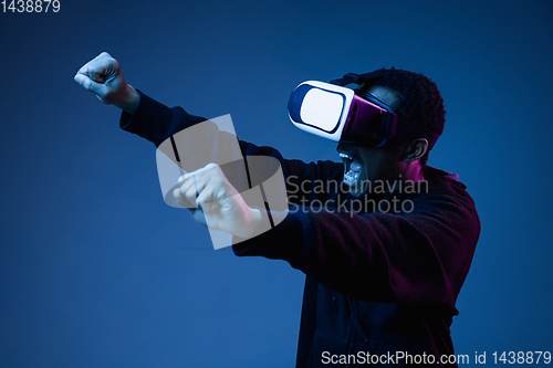 Image of Young african-american man\'s using VR-glasses in neon light