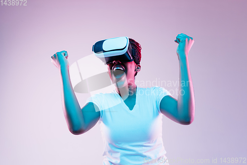 Image of Young african-american woman\'s using VR-glasses in neon light