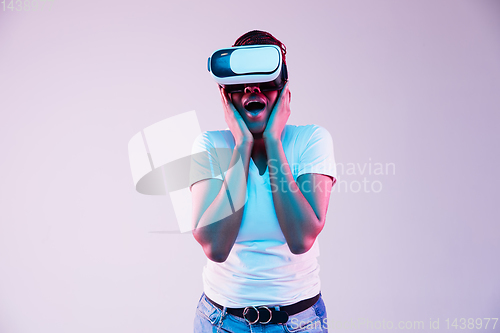 Image of Young african-american woman\'s using VR-glasses in neon light