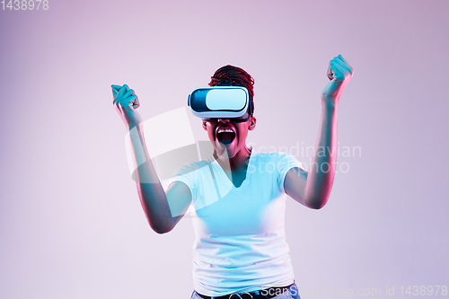 Image of Young african-american woman\'s using VR-glasses in neon light