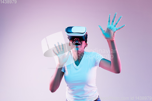 Image of Young african-american woman\'s using VR-glasses in neon light