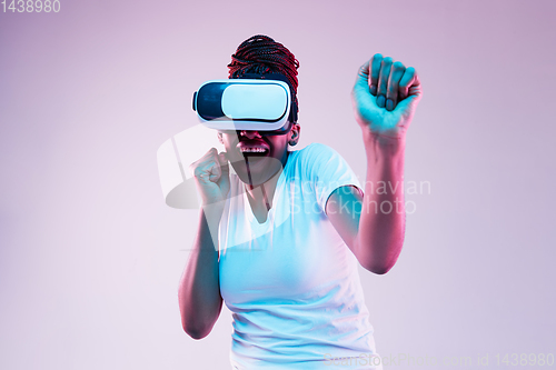 Image of Young african-american woman\'s using VR-glasses in neon light