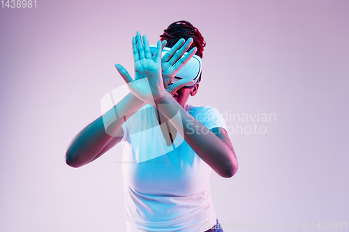 Image of Young african-american woman\'s using VR-glasses in neon light