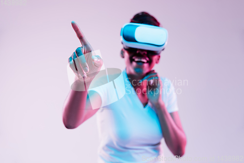 Image of Young african-american woman\'s using VR-glasses in neon light
