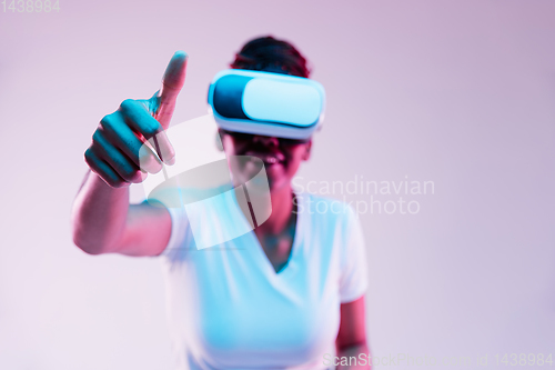 Image of Young african-american woman\'s using VR-glasses in neon light