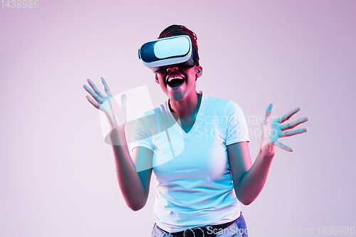 Image of Young african-american woman\'s using VR-glasses in neon light