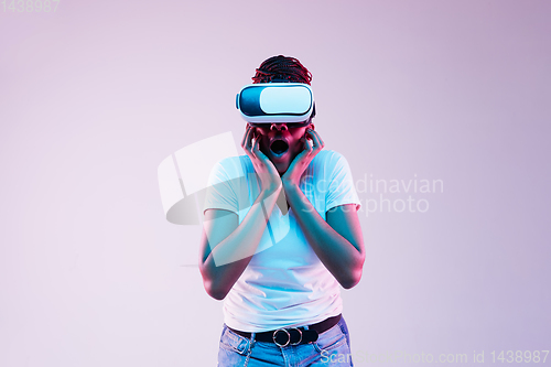 Image of Young african-american woman\'s using VR-glasses in neon light