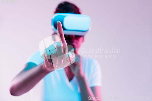 Image of Young african-american woman\'s using VR-glasses in neon light