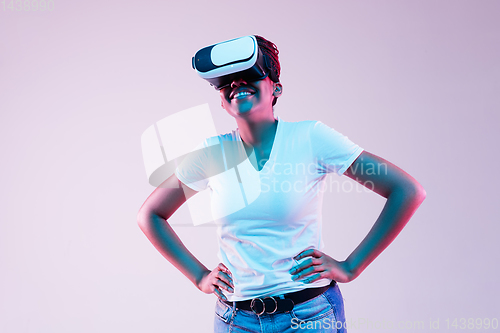 Image of Young african-american woman\'s using VR-glasses in neon light