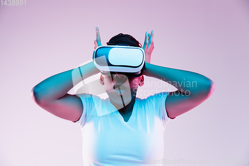 Image of Young african-american woman\'s using VR-glasses in neon light