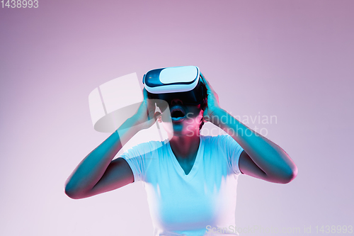 Image of Young african-american woman\'s using VR-glasses in neon light