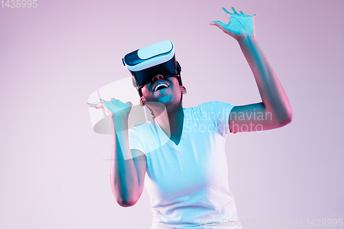 Image of Young african-american woman\'s using VR-glasses in neon light