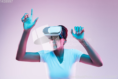 Image of Young african-american woman\'s using VR-glasses in neon light