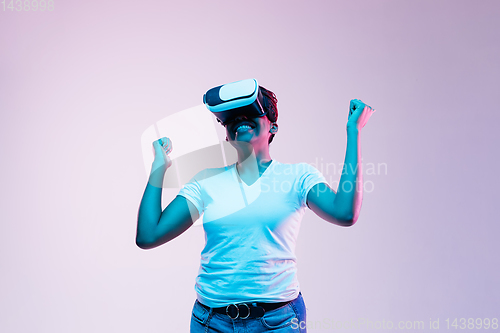 Image of Young african-american woman\'s using VR-glasses in neon light