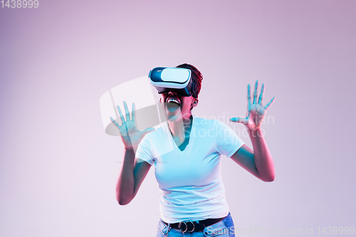 Image of Young african-american woman\'s using VR-glasses in neon light