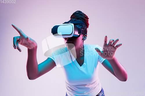 Image of Young african-american woman\'s using VR-glasses in neon light