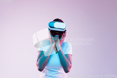 Image of Young african-american woman\'s using VR-glasses in neon light