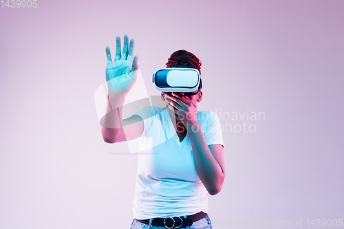 Image of Young african-american woman\'s using VR-glasses in neon light