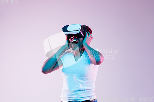 Image of Young african-american woman\'s using VR-glasses in neon light