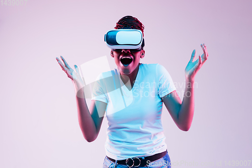 Image of Young african-american woman\'s using VR-glasses in neon light