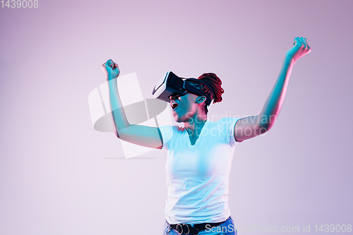 Image of Young african-american woman\'s using VR-glasses in neon light