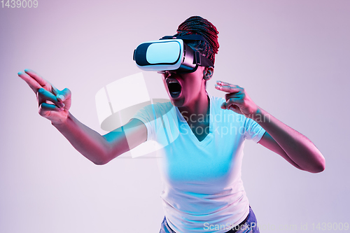 Image of Young african-american woman\'s using VR-glasses in neon light