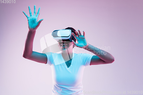 Image of Young african-american woman\'s using VR-glasses in neon light
