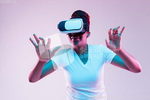 Image of Young african-american woman\'s using VR-glasses in neon light