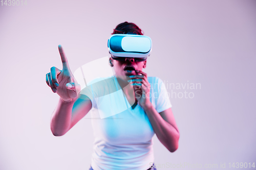 Image of Young african-american woman\'s using VR-glasses in neon light