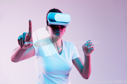 Image of Young african-american woman\'s using VR-glasses in neon light